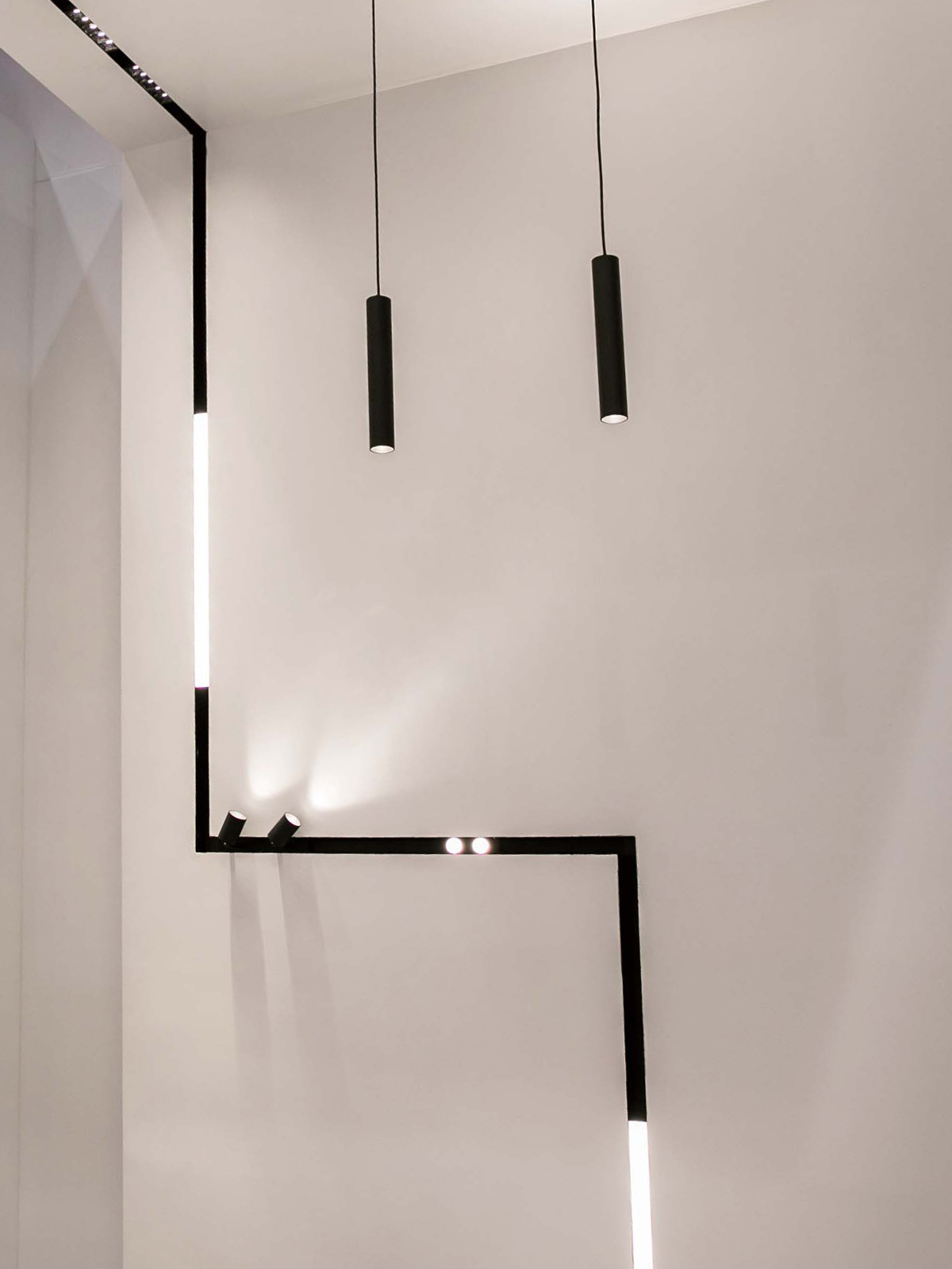 DLD Shadowline recessed track with right angle joints linking from the ceiling to the wall, using linear LED modules, spot lights, pendants and downlights