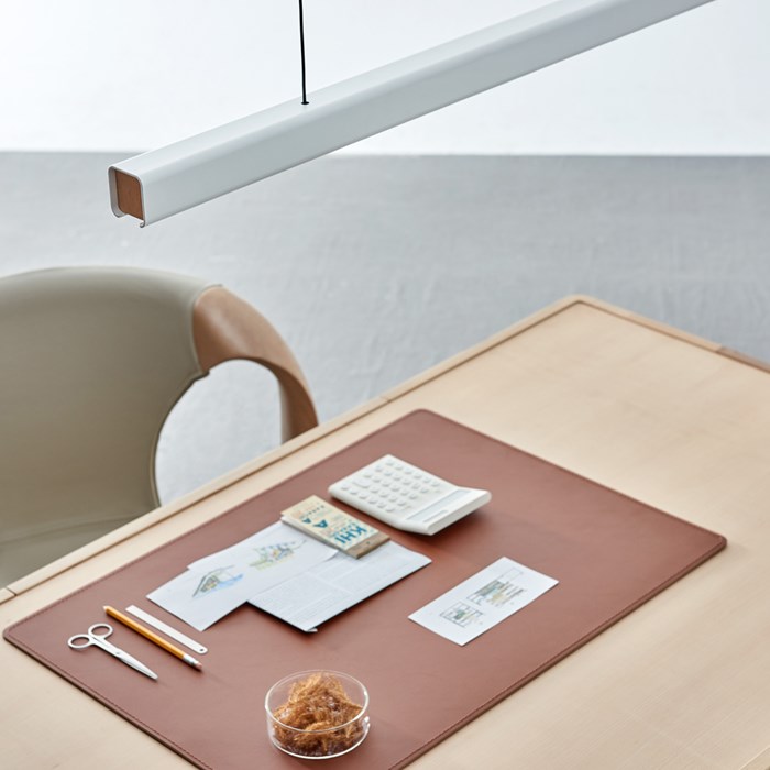The Seed Design white and beech coloured Mumu 120 Pendant suspended above a light wood desk during the daytime