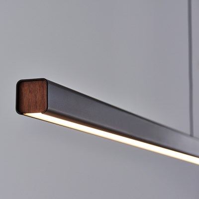 Seed Design close up of Mumu Linear LED Pendant in black with walnut detailing, warm light against. grey background