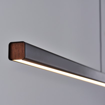 Seed Design close up of Mumu Linear LED Pendant in black with walnut detailing, warm light against. grey background
