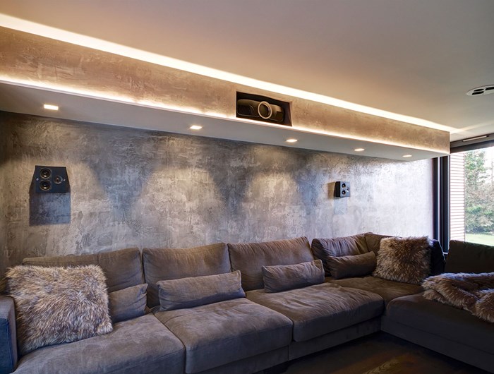 Contemporary and luxurious living room with large corner sofa, lit with atmospheric linear LED profile & tape and adjustable downlights