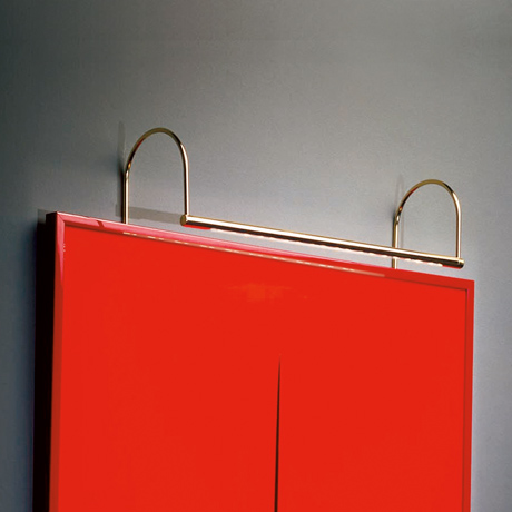 Sleek contemporary designer LED picture light in brass, illuminating a piece of red modern art