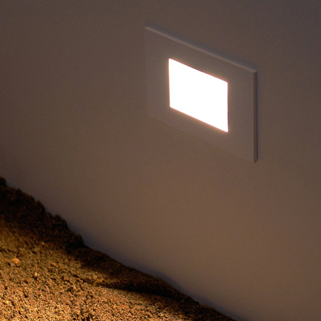 Outdoor low level rectangular LED light recessed into a wall & shining onto the ground