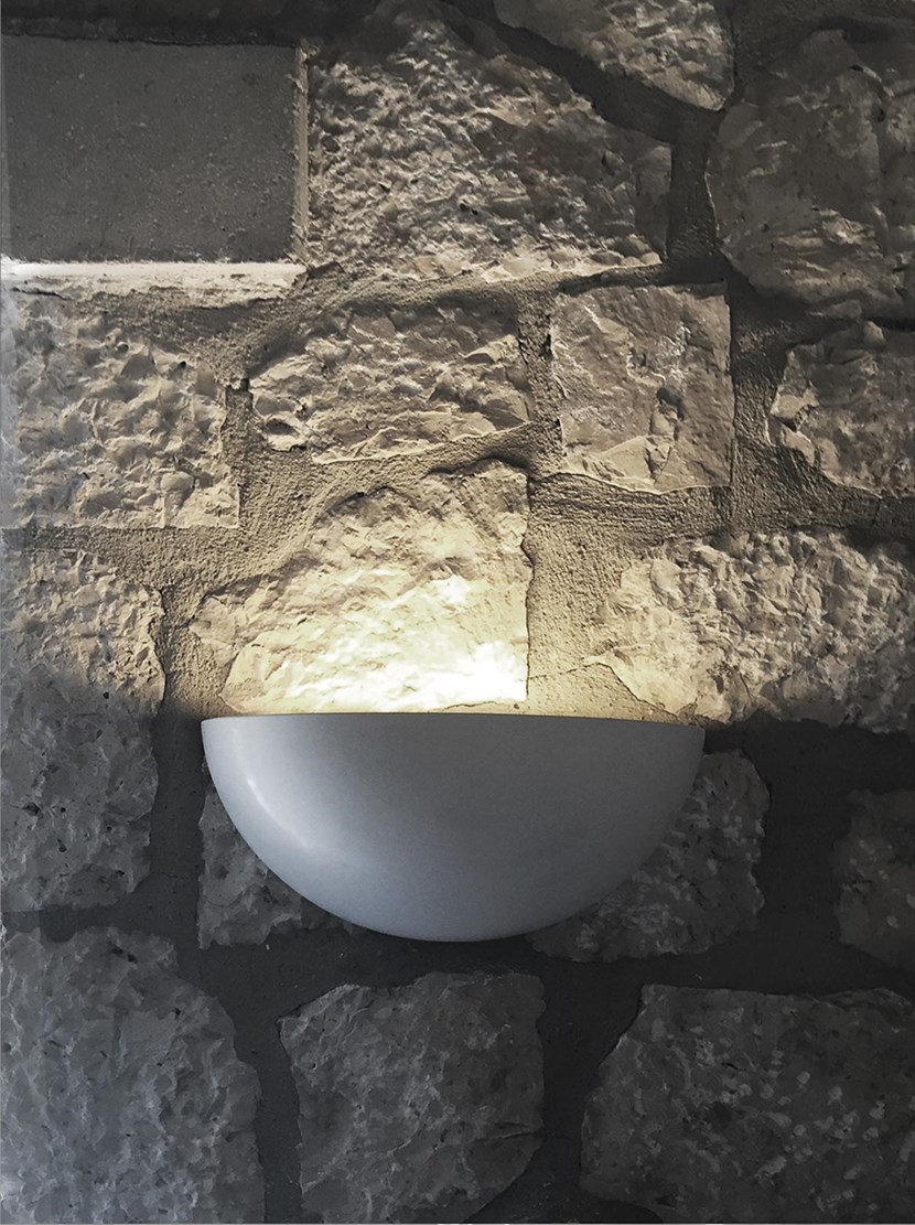 Nama Sfera 01 bowl wall lamp lighting upwards on a rustic stone wall in the evening 