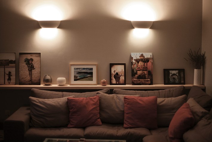 Pair of Nama Sfera 02 bowl wall lamps lighting up and down above a cosy corner sofa and shelf with decorative pictures and ornaments