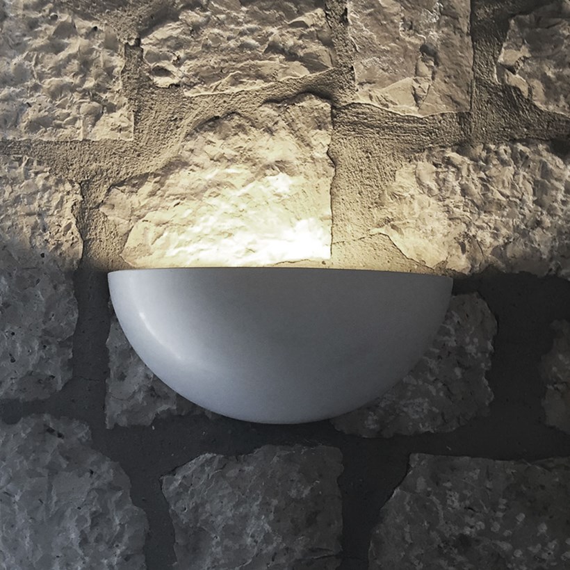 Nama Sfera 01 bowl shaped wall lamp lighting up a rustic stone wall