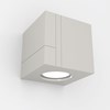 Nama Mondi Down Cube Wall Light switched on, set on a grey background