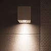 Close up of the Nama Mondi Down Wall Light lighting down a tiled wall in a contemporary bathroom
