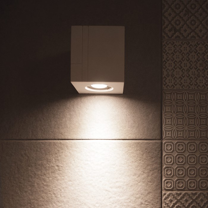 Close up of the Nama Mondi Down Wall Light lighting down a tiled wall in a contemporary bathroom
