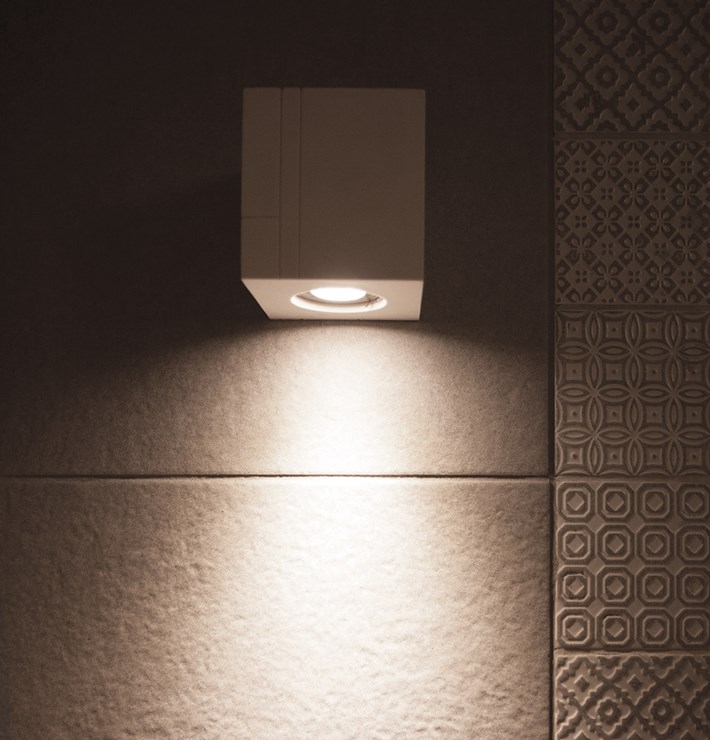 Close up Nama Mondi Down Cube Wall Light lighting down a tiled wall in a contemporary bathroom