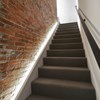 Eleni EL301 linear profile cornice uplighting an exposed brick wall on a set of stairs