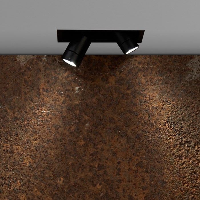 Flexalighting's Minileda QX120 in a lifestyle image, shining a rusty concrete wall.