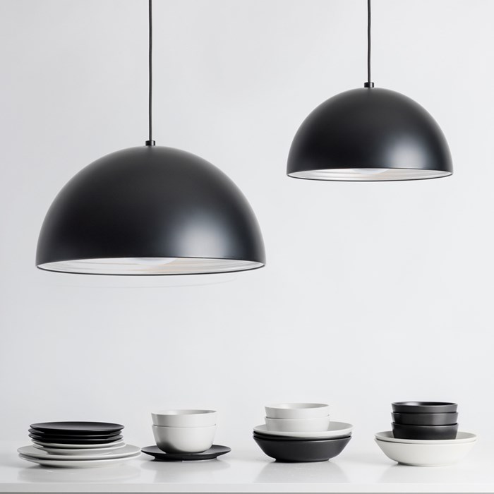Pair of Seed Design Dome matt black pendants in medium & large over white table with monochromatic crockery