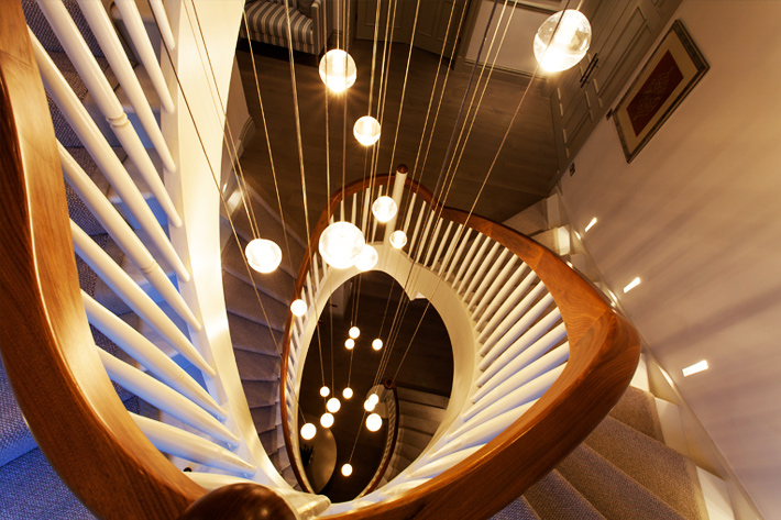 Premium Lighting Design - birds eye view from above of a Bocci glass orb cluster of pendants, suspended at various heights down a large round staircase