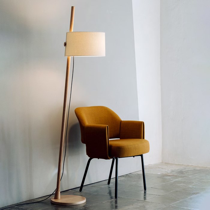 Milan Iluminacion Linood Floor Lamp with slanted base in oak in a contemporary space next to a mid century mustard fabric armchair