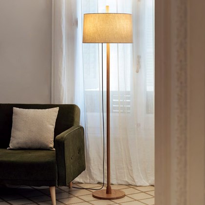 Milan Iluminacion Linood Straight Floor Lamp in oak in a modern living room next to a mid century green fabric sofa
