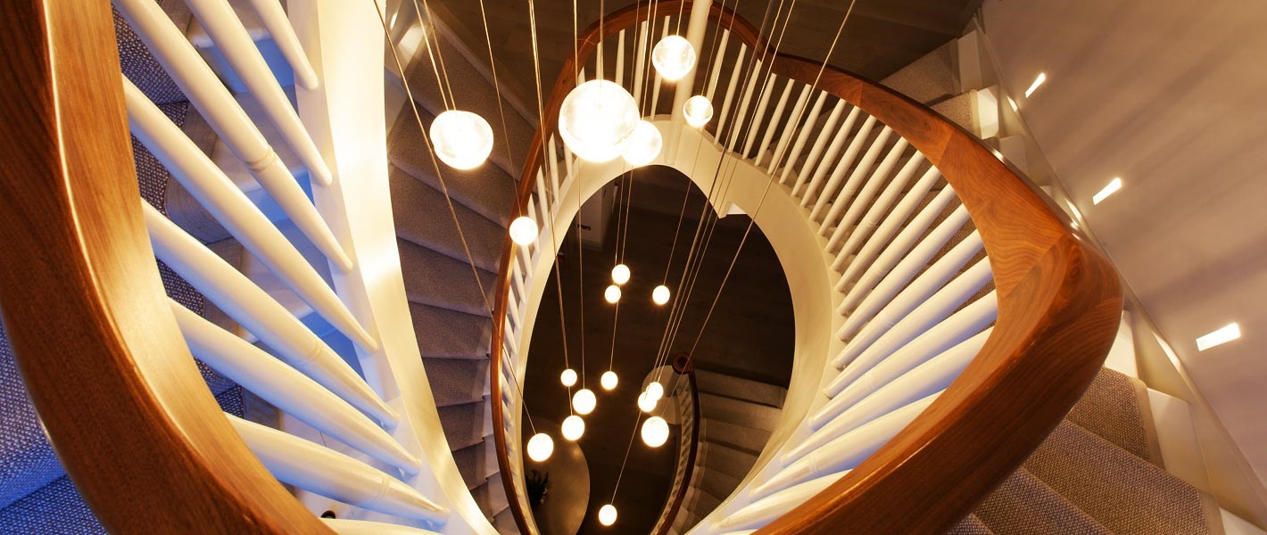 Premium Lighting Design - cluster of Bocci pendants suspended at multiple levels down a 3 storey spiral staircase