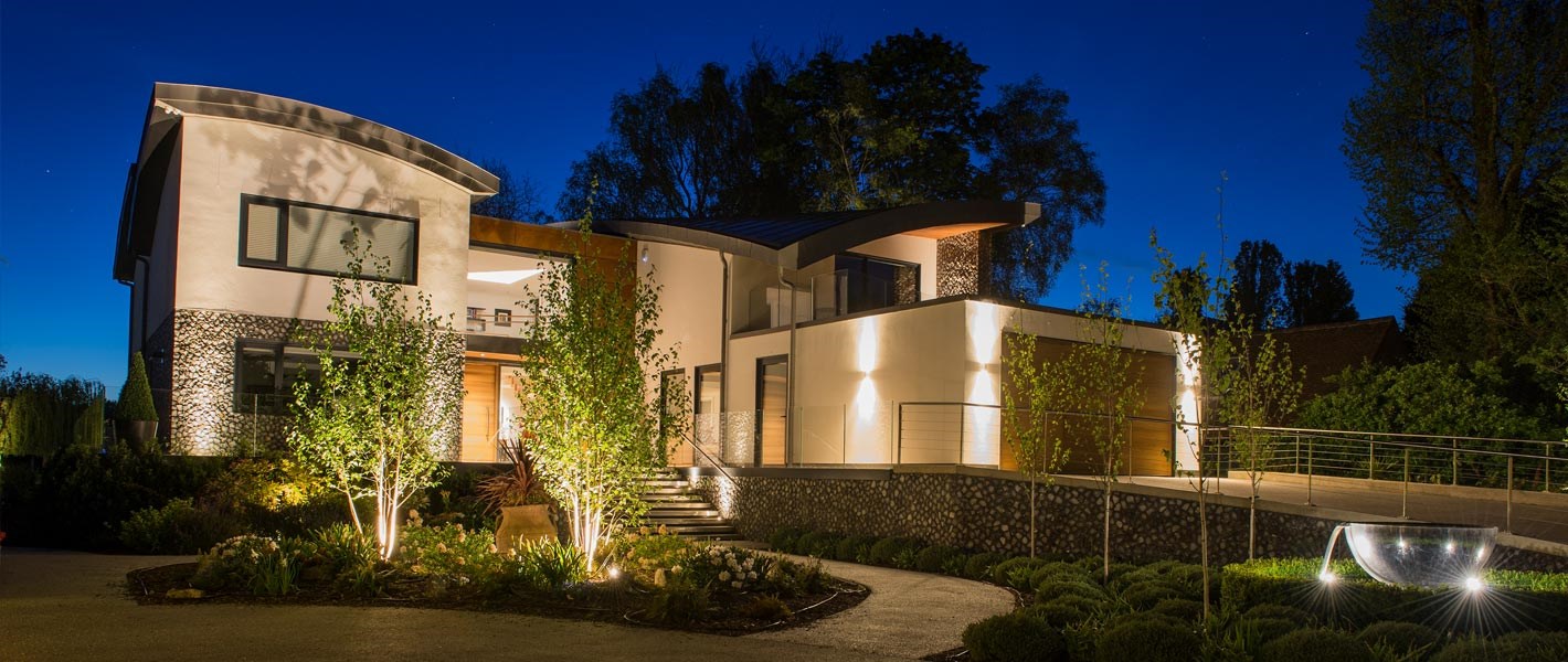 Outdoor shot of a spectacular and contemporary home and front grounds lavishly lit at night 