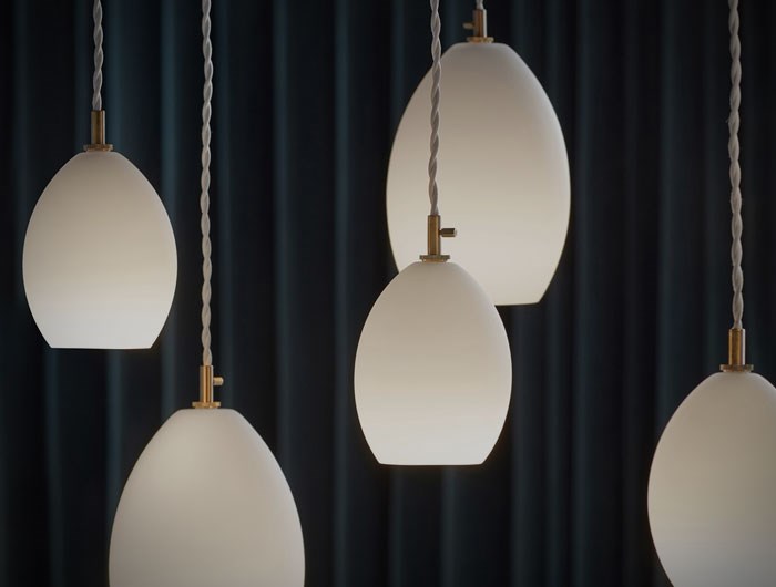Cluster of suspended contemporary egg shaped opaque glass pendants with industrial brass detailing