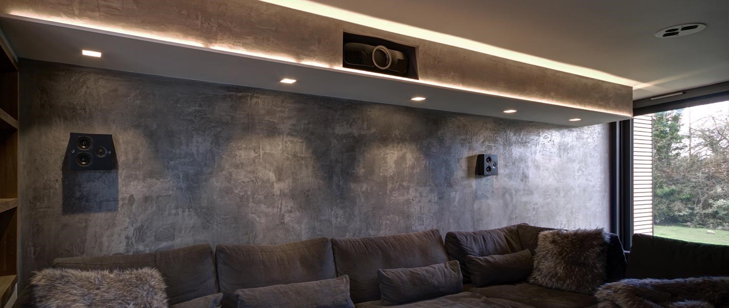 Contemporary & luxurious living room with large corner sofa, lit with atmospheric linear LED profile & tape & adjustable downlights