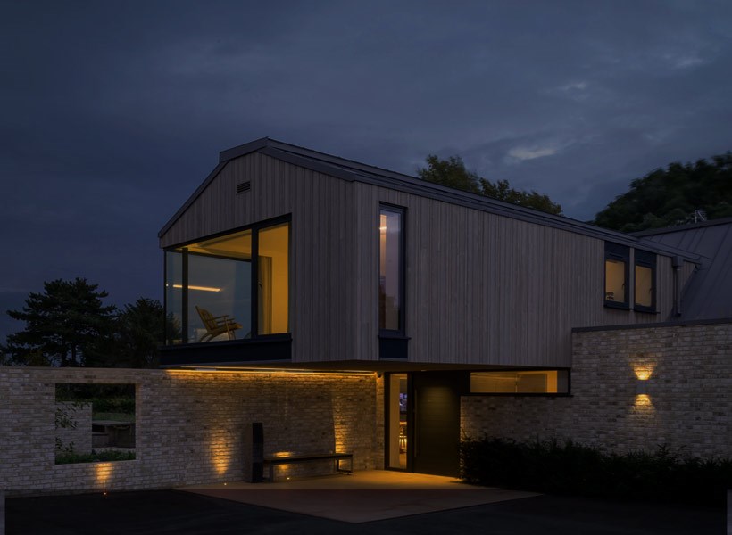 Modern minimalist cantilever house at night with smart home lighting and outdoor landscape lighting