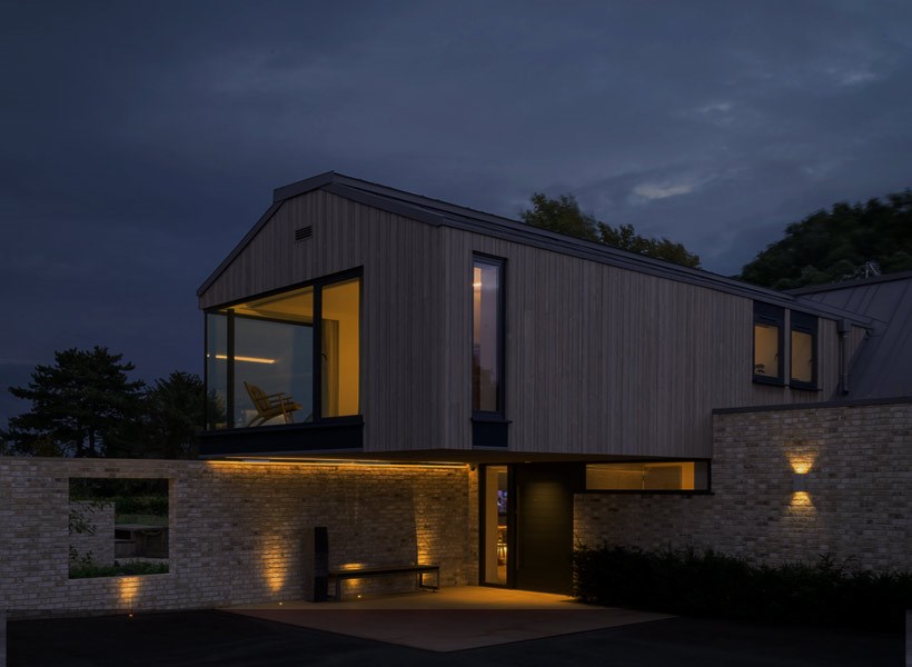 Modern minimalist cantilever house at night with smart home lighting and outdoor landscape lighting