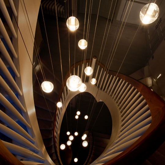 Staircase Pendant Lighting: Looking down a spiral staircase at a cluster of spherical glass pendants suspended at various heights