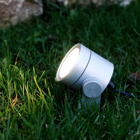 Outdoor LED floodlight / spotlight mounted in the grass at dusk