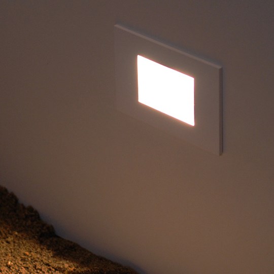 Outdoor low level rectangular LED light recessed into a wall & shining onto the ground