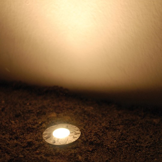 Outdoor Recessed Uplights: Exterior recessed round LED uplight installed in the ground & shining a warm white light up a wall