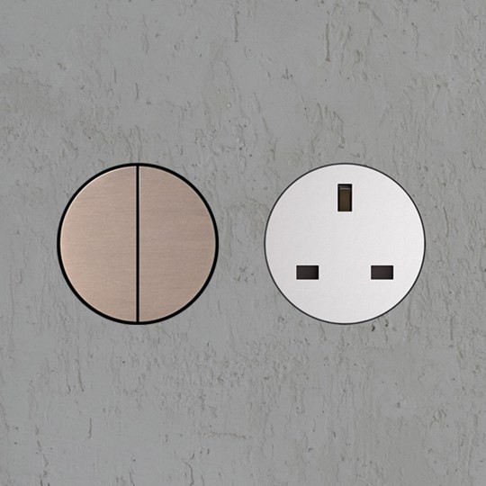 Sockets & Switches: Architectural brushed bronze round wall switch and white round switchless UK power socket installed in plastered wall