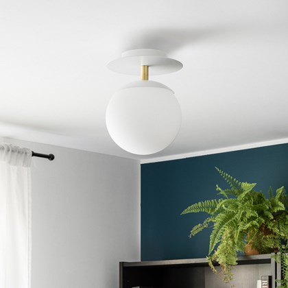 Side shot of circular wall light with white glass globe, black disc, and brass supporting tube shown against white background.  alternative image