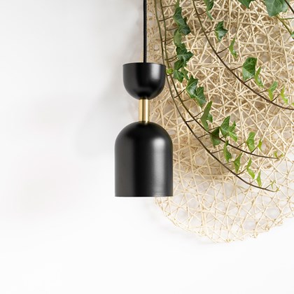 Black metallic pendant light with brass tube connecting two elongated hollow dome shapes.  alternative image