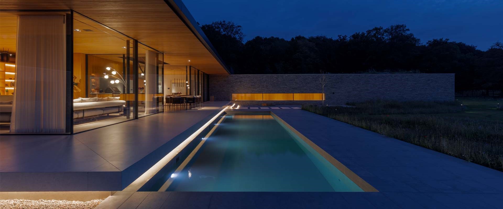 Lighting Design Services: modern home with outdoor swimming pool lit at night