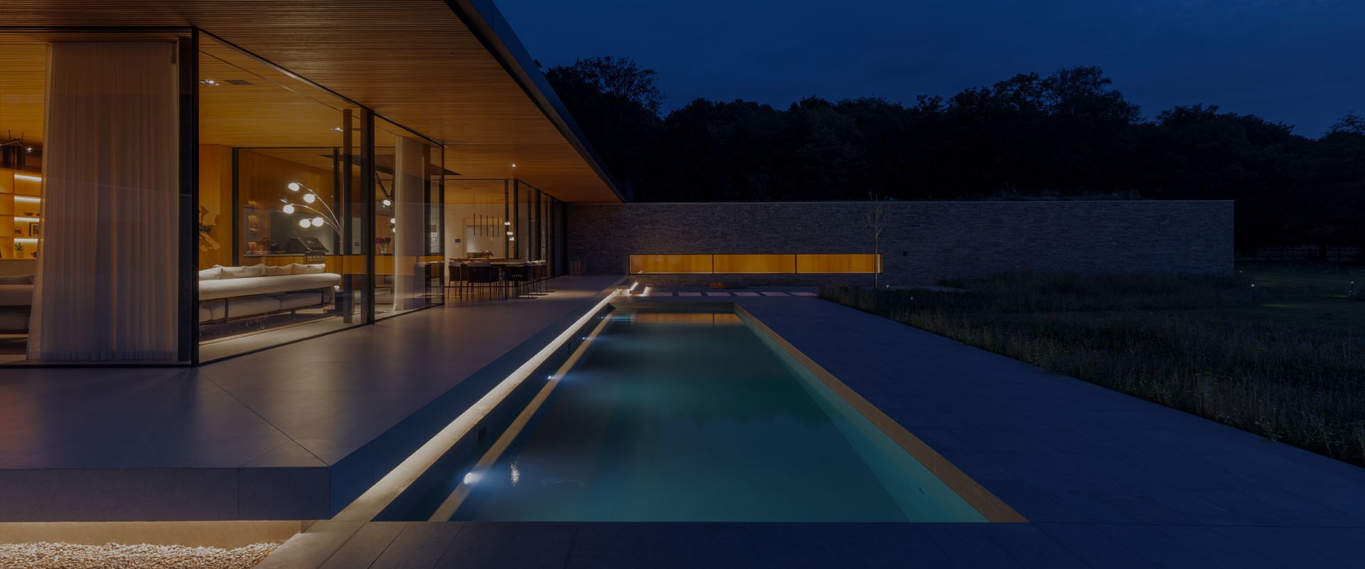 Lighting Design Services: modern home with outdoor swimming pool lit at night