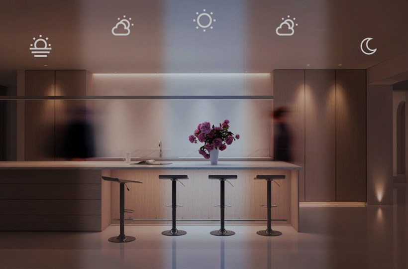 A minimalist contemporary kitchen with human centric lighting split into 5 sections, each one showing the different light temperature and brightness used for different parts of the day, with time-lapse blurred man and woman behind the kitchen island