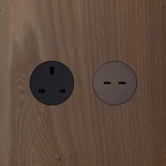 Architectural Lighting: rond UK round switchless power socket in black and round USB-C twin charging port in brushed bronze installed in a wooden panel