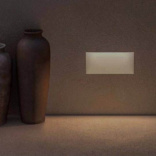 Architectural Lighting: rectangular plaster-in wall mounted low level step light, lighting the floor with a earthenware vase in foreground 