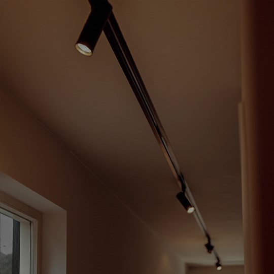 Architectural Lighting: black trimless track system running down a hallway with 5 adjustable spot light modules