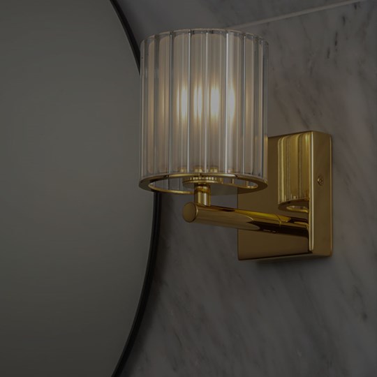 Indoor Lighting: IP rated wall light in gold with glass shade installed in a bathroom next to a round mirror